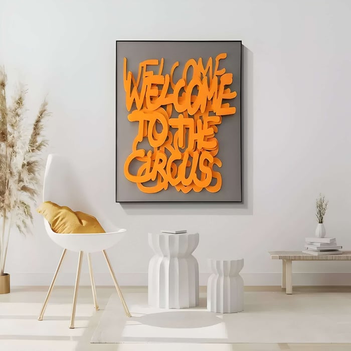 White interior with a bright orange 3D text artwork reading ‘WELCOME TO THE CIRCUS’ above modern decor