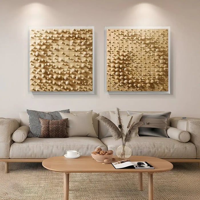 A set of two textured golden wall art pieces with geometric shapes and patterns, displayed above a neutral-toned sofa with decorative pillows in a stylish living room.