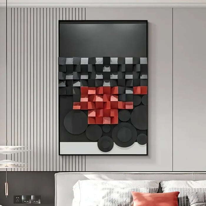 A modern bedroom featuring a large three-dimensional abstract artwork with black, white, and red geometric shapes mounted on a light grey wall. The room includes a neutral upholstered headboard with decorative pillows, a sleek pendant light, and a contemporary bedside setup.