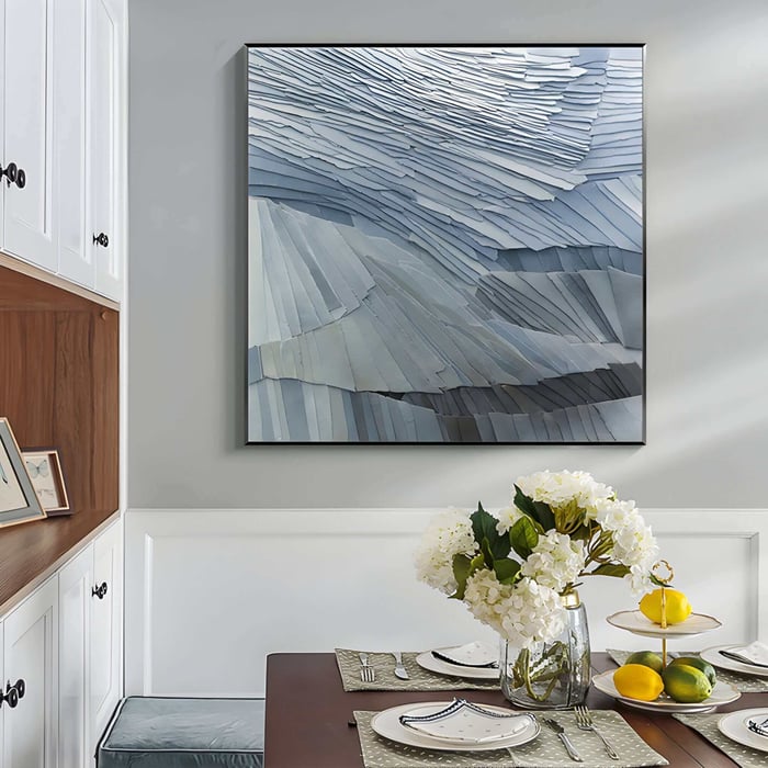 Large blue-toned abstract wall sculpture with layered textures above a dining table with floral decor.