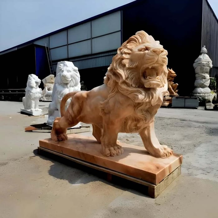 Large carved lion wildlife sculpture displayed outdoors at sculpture workshop yard.