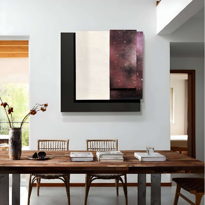Geometric wall art featuring layered rectangular panels in cream, black, and galaxy print above a rustic table.