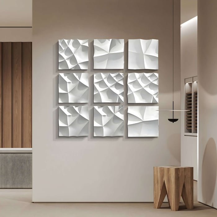 Grid of abstract white 3D panels with folded, wave-like surfaces mounted on a neutral hallway wall.