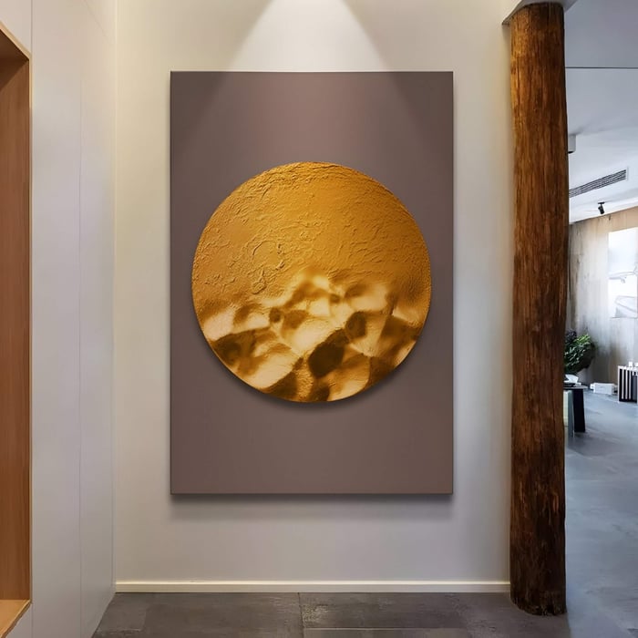  Golden circular wall sculpture with a sand-like texture pops against a matte brown backdrop in a softly lit hallway.
