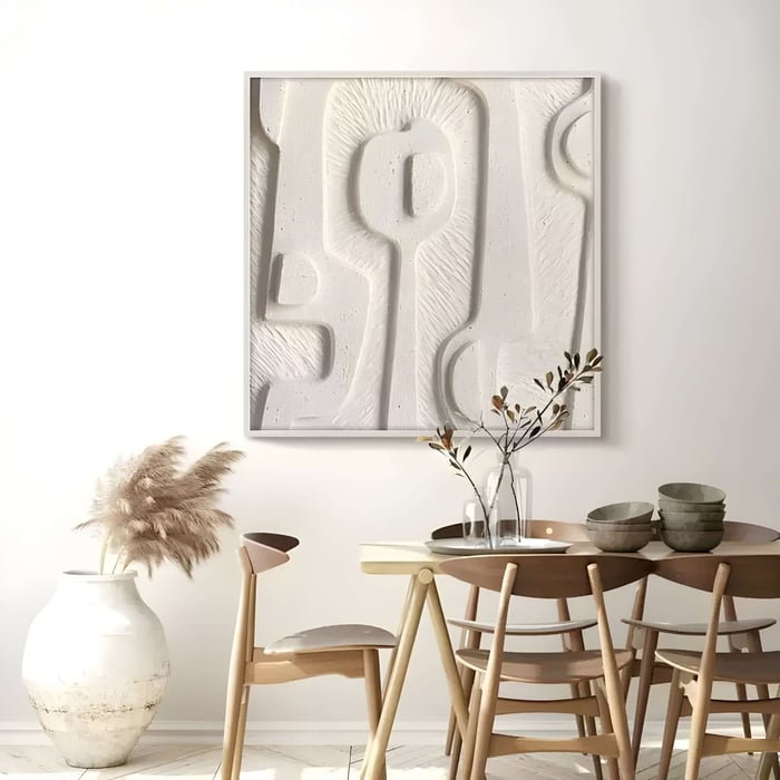 Minimalist white textured wall art with carved shapes, paired with wooden furniture and neutral decor.