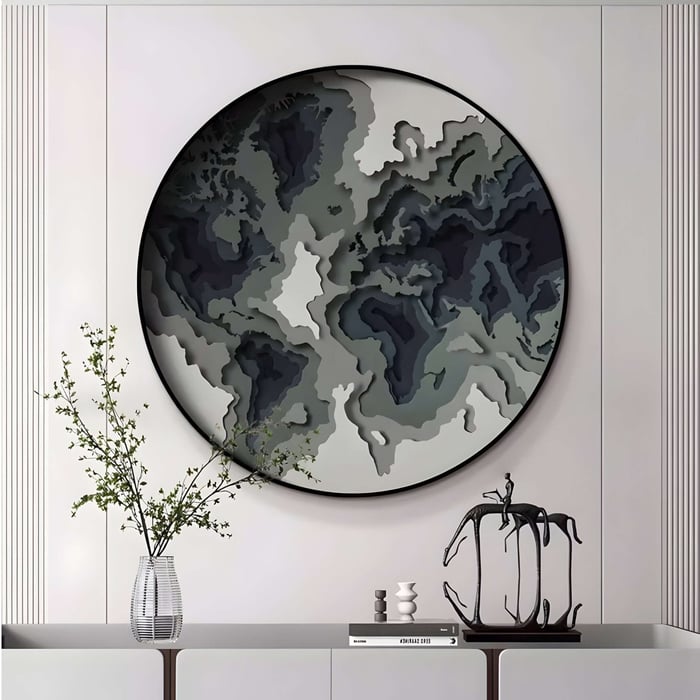 Large round wall art resembling a layered topographic map in grayscale above a sculptural decor console.