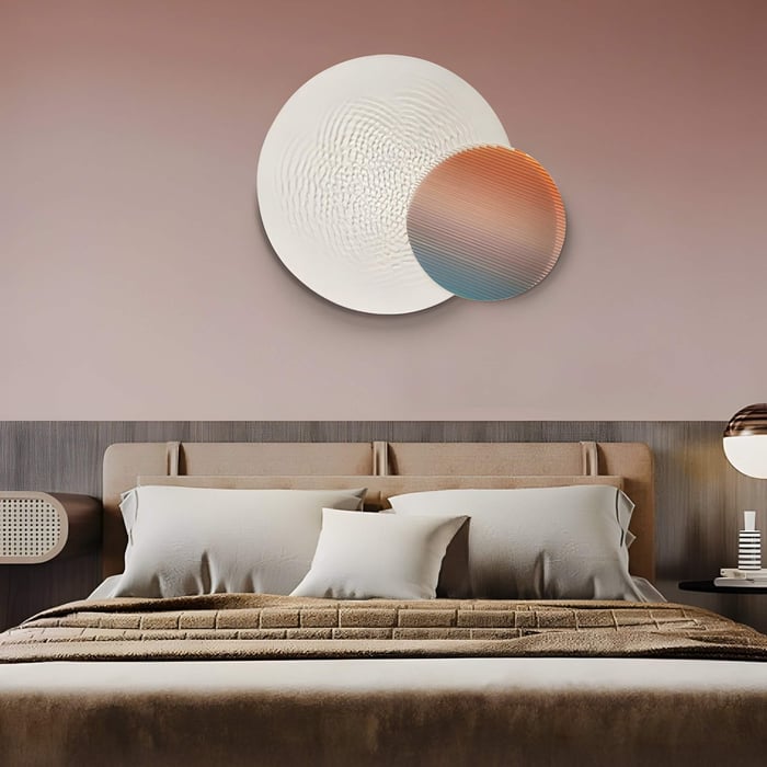 A modern bedroom art showcases a beige upholstered bed, pillows, and a textured duvet. On the wall are two overlapping circular art pieces from Giant Sculptures: Lucentis White & Sunset Gradient 3D Wood Relief Wall Art. A lamp on a side table complements the soothing decor.