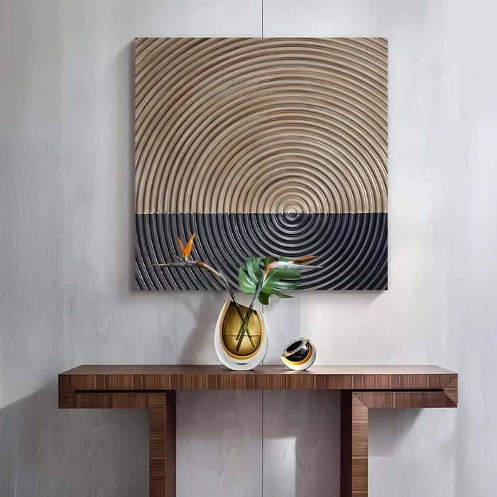 Textured concentric circle wall art in neutral tones above a console table with a vase and sculptural objects.