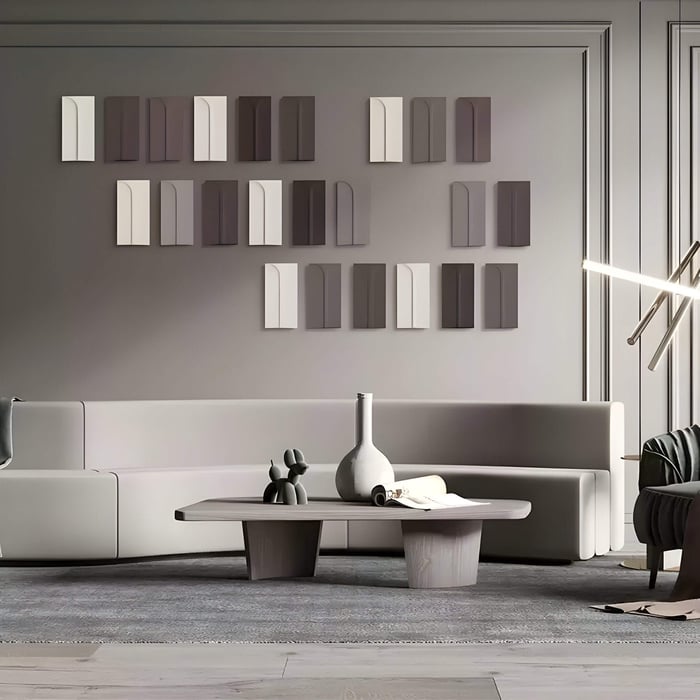 Geometric 3D wall art with neutral tones arranged above a minimalist beige sofa in a modern, monochrome living room setting.