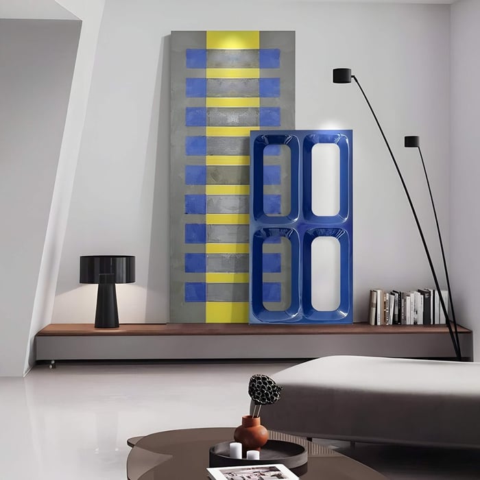 Contemporary office art with bold blue and yellow geometric patterns, leaning against a minimalist wall with books and decor.