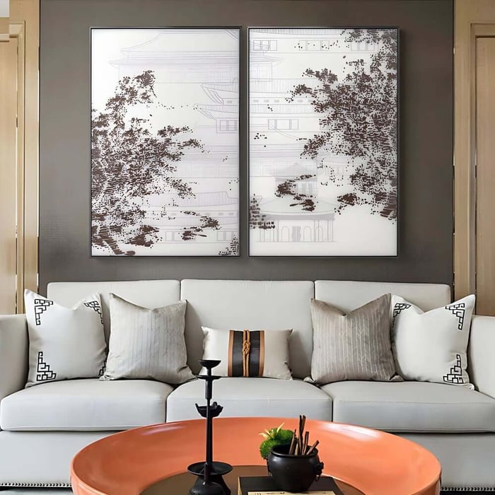 Two framed monochrome panels with tree silhouettes above a sofa in a modern neutral-toned space.