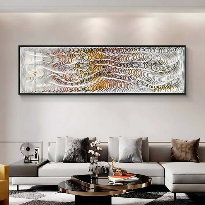 Panoramic abstract wall art with flowing white and gold waves above a contemporary grey sofa.
