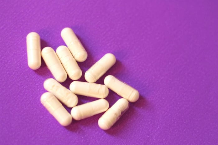 A pile of white pills sitting on top of a purple surface