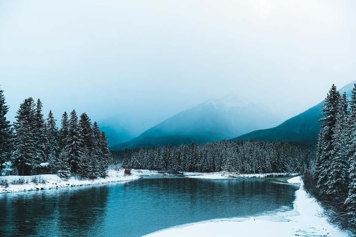 Ein See, umgeben von schneebedeckten Bäumen und Bergen