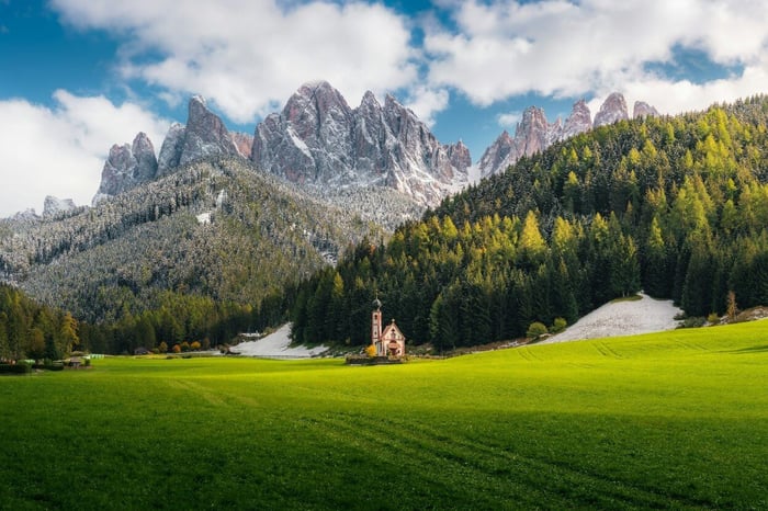 Grünes Grasfeld in Bergnähe unter blauem Himmel tagsüber