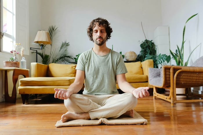A man meditating cross-legged on a wooden lounge floor