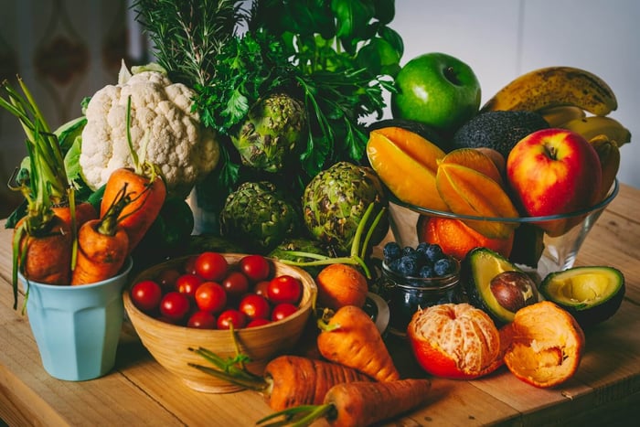 A collection of healthy foods on a wooden table stacked up in bowls and in piles