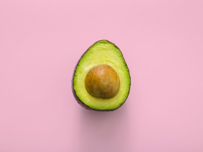 An aesthetic product shot of half an avocado on a pink background