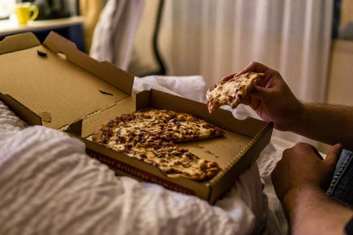Someone eating before bed with pizza in a room with the lights dim presumably before going to sleep.