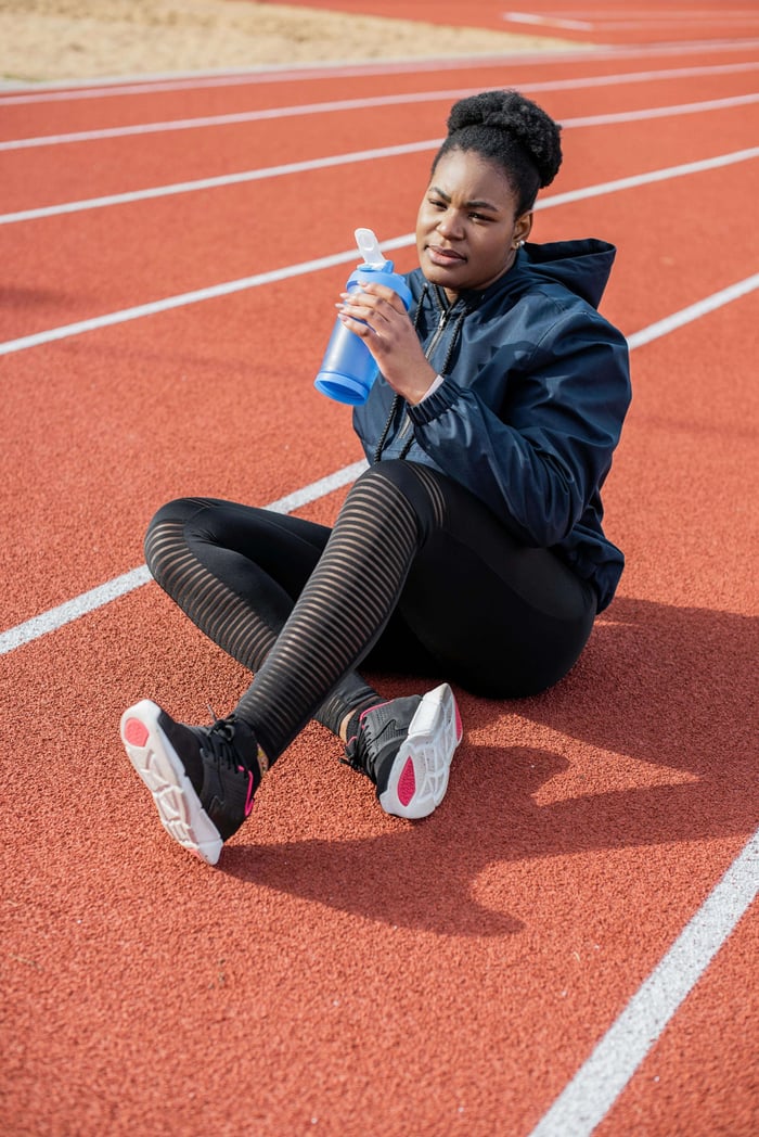 woman drinking water after a track workout in order to stay hydrated
