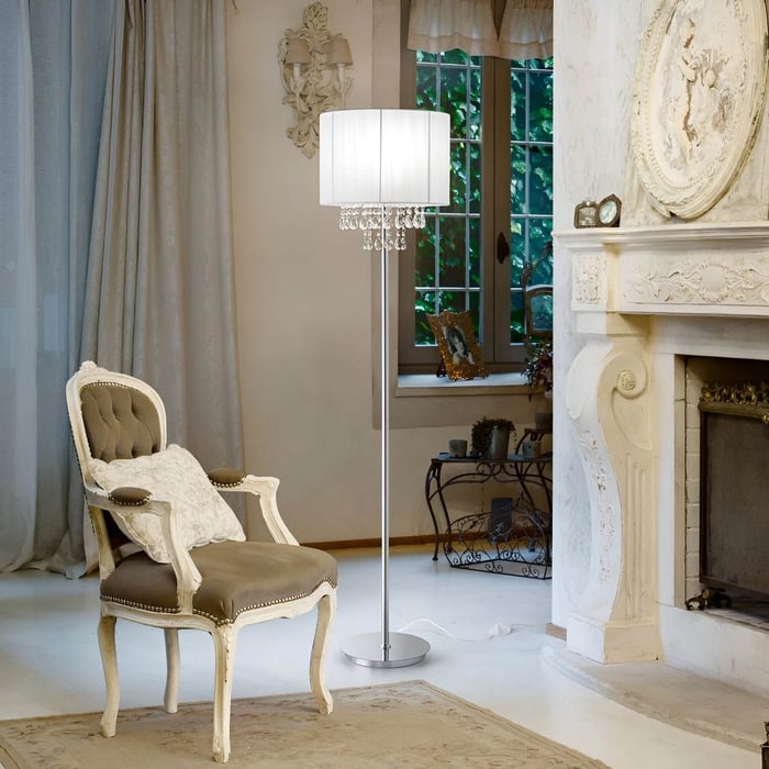 Chrome floor lamp with pleated drum shade and hanging crystals in a classic white sitting room with ornate detailing.