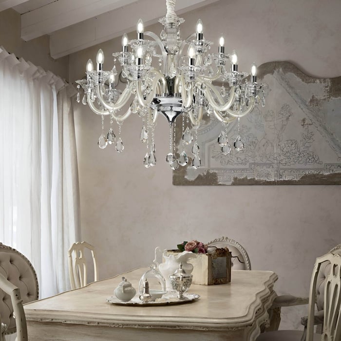 Crystal and ivory chandelier above a vintage dining table with ornate chairs and antique-style decor.