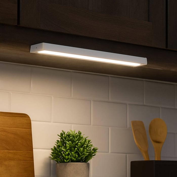 Warm under-cabinet LED strip light creating cosy task lighting over a kitchen counter and tiles.