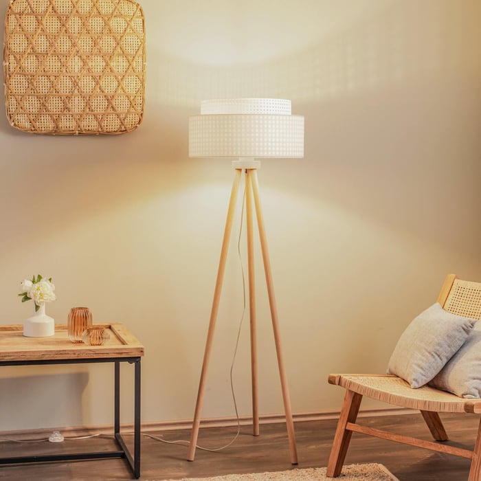 Tripod floor lamp with patterned drum shade casting warm glow in a natural-toned interior.