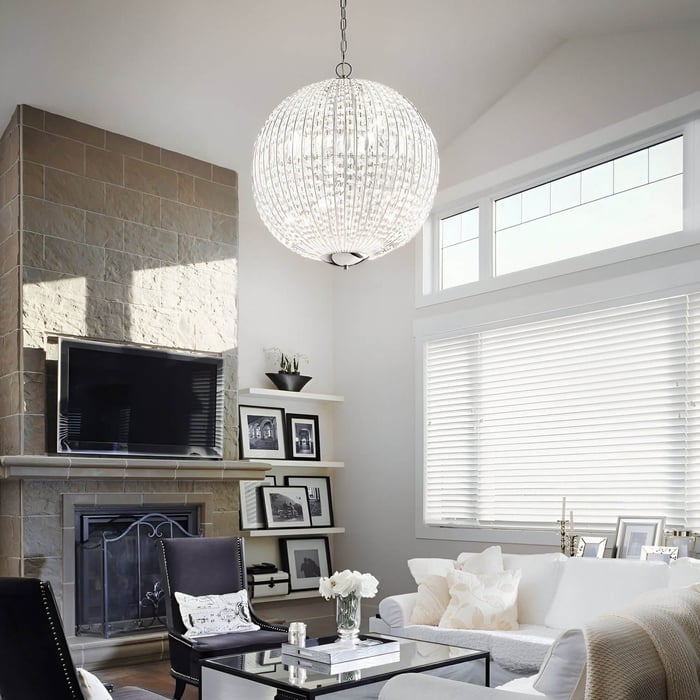 Elegant lounge with layered curtains, gray furnishings, and crystal chandeliers hanging from a traditional white ceiling.