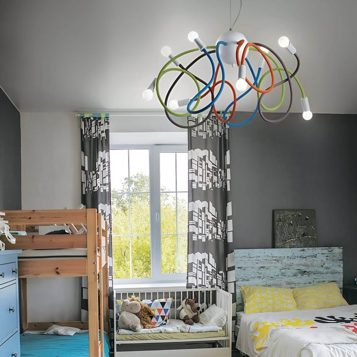 Colorful children's room with looping multicoloured tube ceiling light above bunk bed and cot.