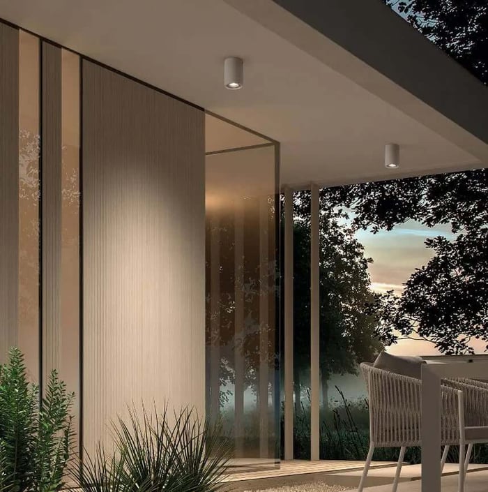 Recessed outdoor downlights installed in a clean-lined overhang beside floor-to-ceiling glass.