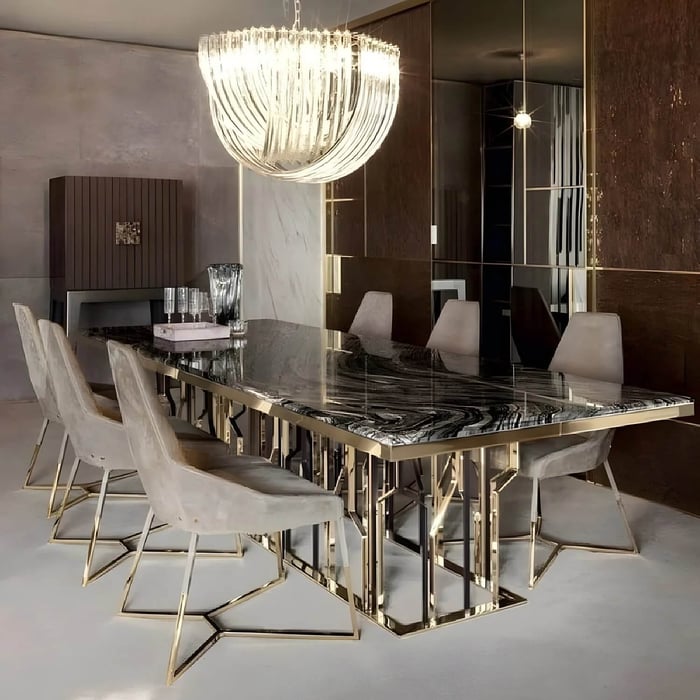 Large curved glass chandelier suspended above a long marble dining table in a luxe modern dining room with brass accents.