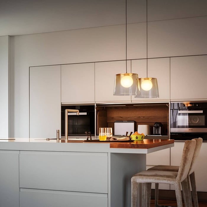 Contemporary kitchen with pendant glass lights, sleek cabinetry, and a cozy bar seating area.