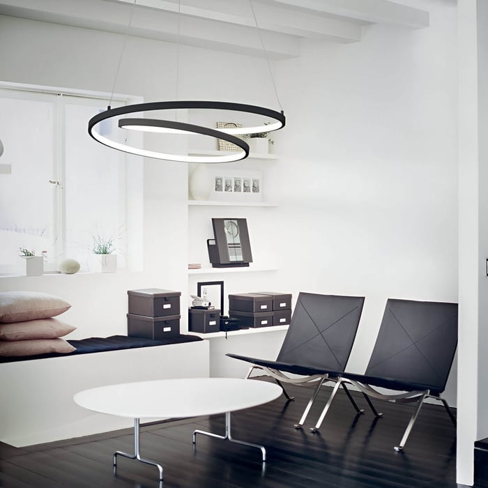 Contemporary office space with a dual black spiral ring pendant light above a white round table and black chairs.