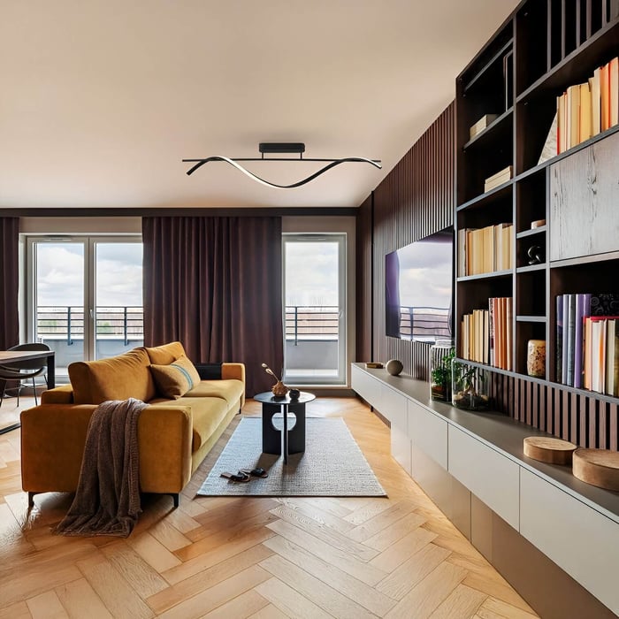 Living room ceiling light — Warm living room with mustard sofa, bookshelves, and a sleek, wavy black LED ceiling light.