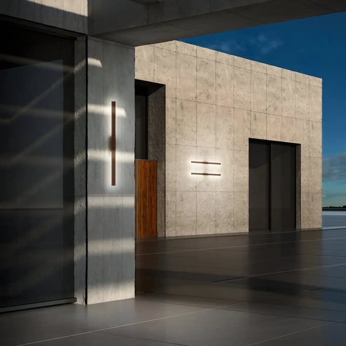Contemporary concrete building with sleek vertical and horizontal outdoor wall lights creating sharp shadows at sunset.