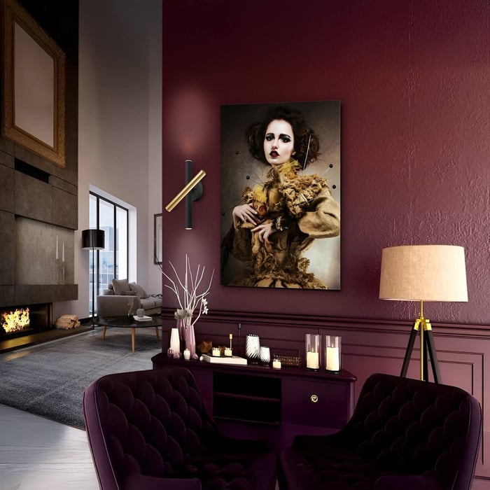 Luxurious living space with burgundy walls, velvet seating, a dramatic portrait, candles, and a sleek gold-and-black wall sconce.