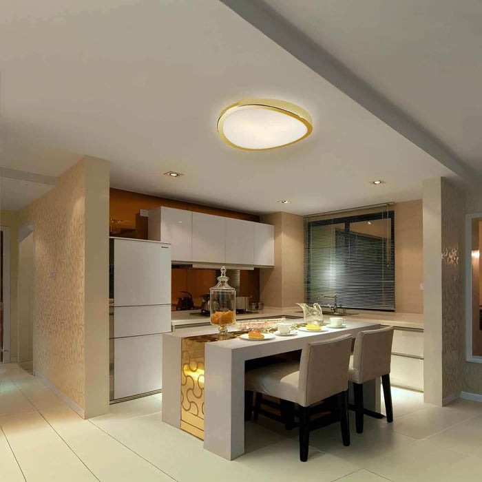Modern kitchen and dining area with a round flush ceiling light featuring a gold trim ring.