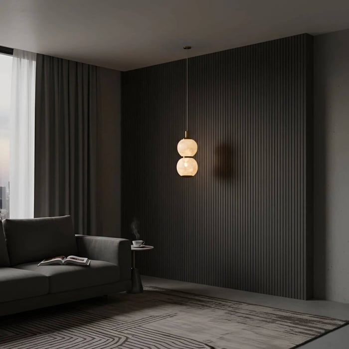 Double globe alabaster pendant light against a dark textured feature wall in a cosy lounge setting.