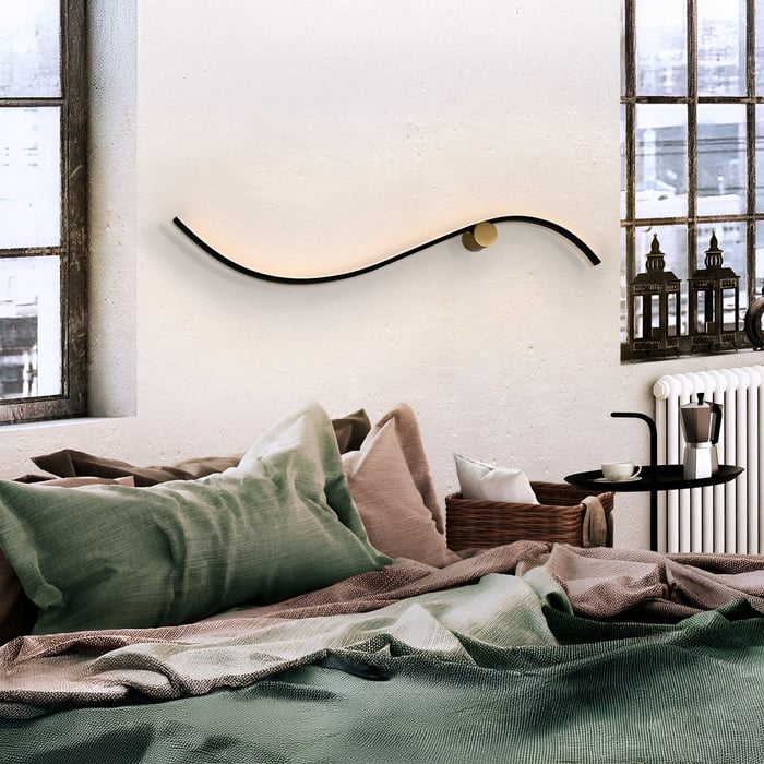 Cozy bedroom with a curved wall light above the bed and warm, textured bedding.