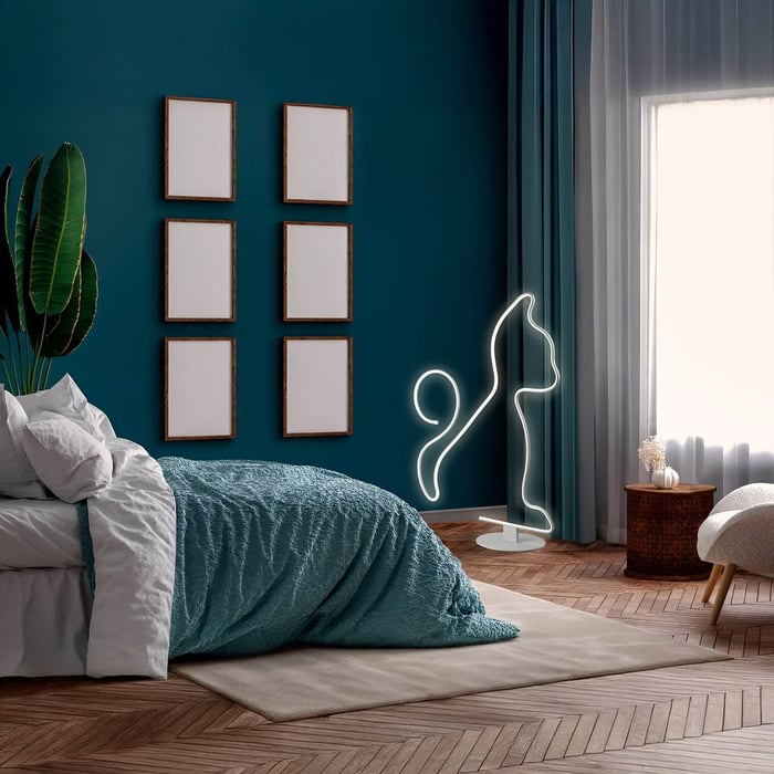 Playful bedroom lights shaped like a cat in neon, set against a teal wall with parquet flooring and a woven side table.