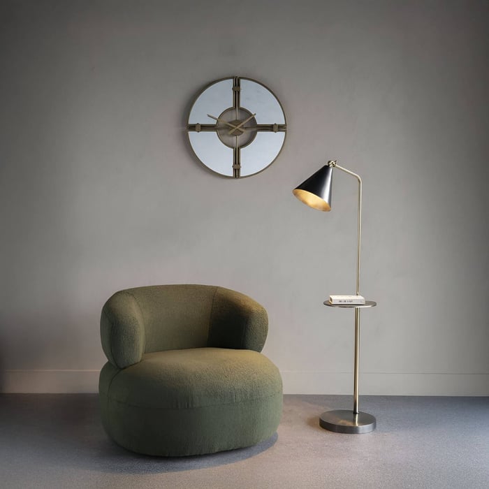 Sleek black floor lamp with conical shade and built-in tray table beside a green lounge chair.