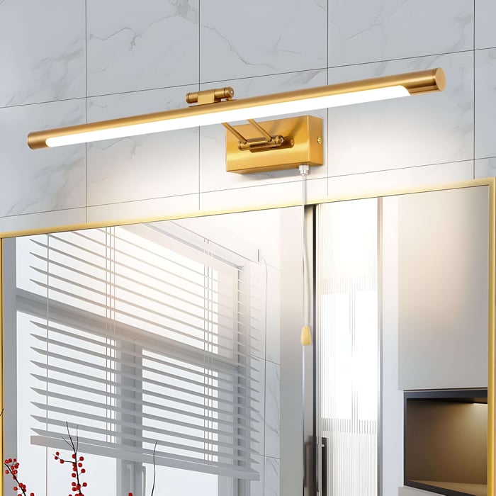 A modern gold picture light mounted above a bathroom mirror, providing warm and focused lighting. The background includes white tiled walls and sleek fixtures.
