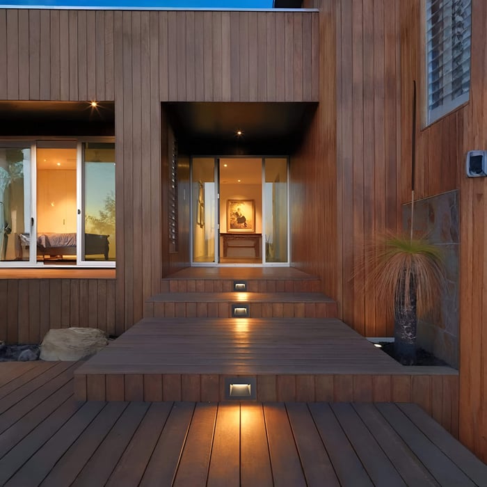 Contemporary timber entry deck with recessed step lights centred on each riser, creating a clear, gentle route to the front door.