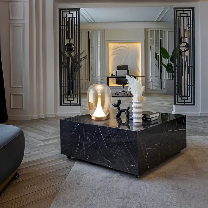Contemporary living space with black marble coffee table, sculptural glass lamp, and view into a modern home office with ambient backlighting.
