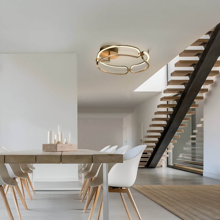Open dining space with wooden table, white chairs, and gold geometric ceiling light.