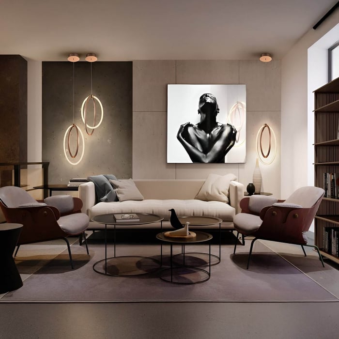 Contemporary living room with a neutral sofa, accent chairs, circular nesting coffee tables, and artistic ring pendant and wall lights against a textured feature wall.
