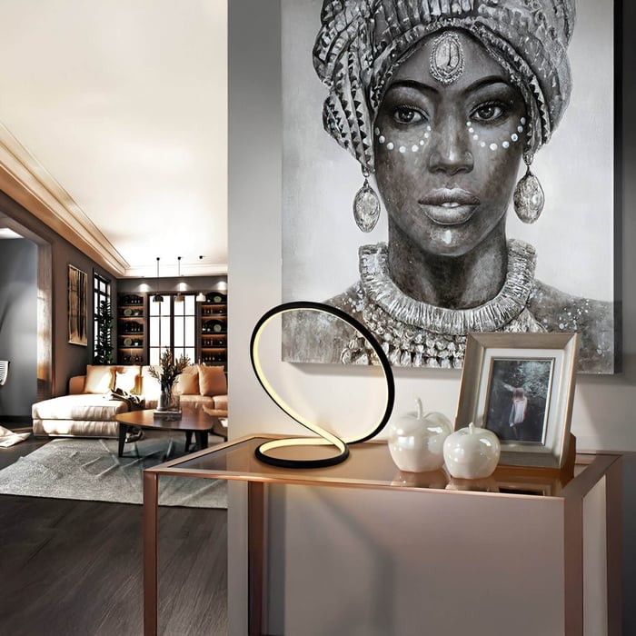 Contemporary console table with a sculptural LED lamp, decorative apples, and a framed photo, set against a large portrait artwork.