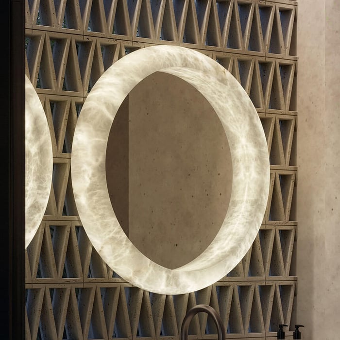 Large circular alabaster mirror with illuminated stone frame mounted on textured architectural wall.