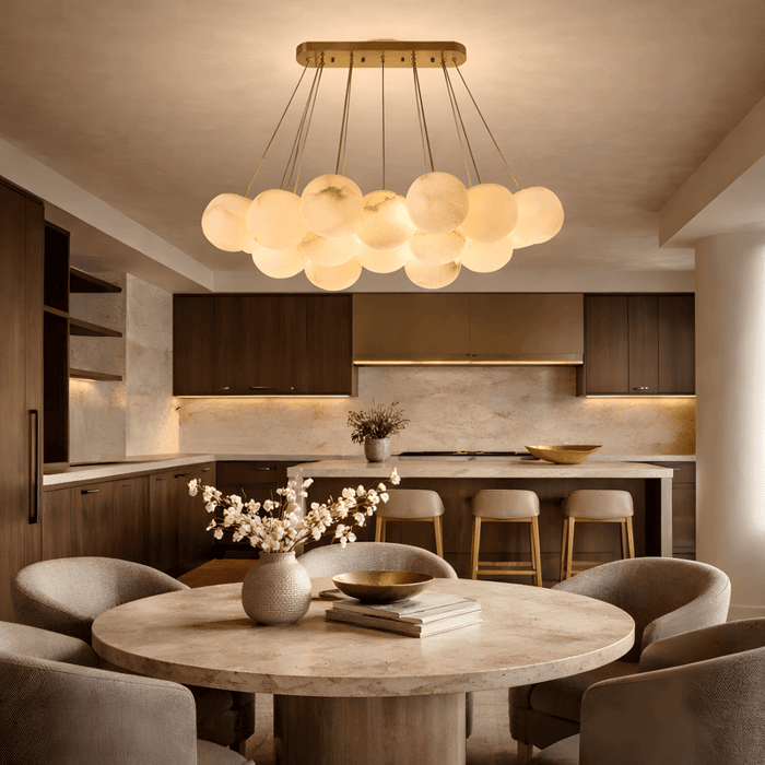 Modern dining area with a clustered alabaster ceiling lights suspended above a round stone table in a warm wood kitchen interior.